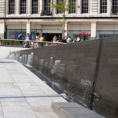 a man riding a skateboard down the side of a wall next to a sidewalk