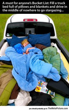 a woman is sleeping in the back of a truck with blankets and pillows on it