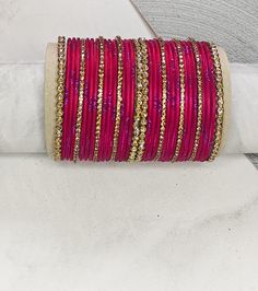 "Medium Stack of Dark Pink & Golden Stones Bangles Set- Beautiful occasion wear jewellery The perfect fusion of tradition and style, designed to elevate your outfit with elegance and charm. This Bangle set is made for two hands and contains 17 pieces in each set. If you want to match the design shown in the picture in single hand, be sure to select a quantity of 2. Notes: Sizes for bangles are Indian sizes so check your exact size as shown in picture before placing and order. Create beautiful memory for any occasion with elegant jewelry for your loved ones" Traditional Pink Bangle For Festive Season, Bangle Set Pink, Pink Bangles Set Indian, Cheap Traditional Pink Bangle, Festive Pink Cutdana Bangle, Bangles Indian, Stone Bangle, Bangle Set, Elegant Jewelry