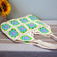 a crocheted bag sitting on top of a table next to a sunflower