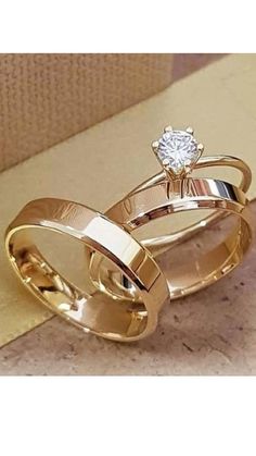 two gold wedding rings sitting on top of each other