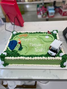 a green birthday cake with a golf theme on the side and a white truck parked in front of it