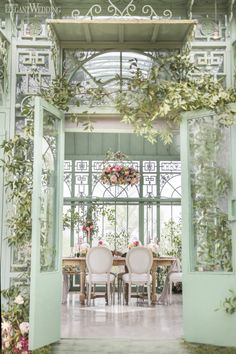 the dining room is decorated with greenery and white chairs, along with pink flowers