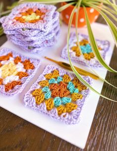 four crocheted coasters sitting on top of a table next to a plant