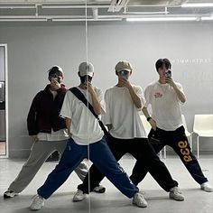 four young men standing in front of a mirror with one holding a cell phone to his ear