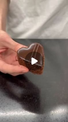 a person holding a heart shaped chocolate cookie