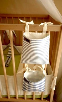 a baby crib with a blue and white striped bag hanging from it's side