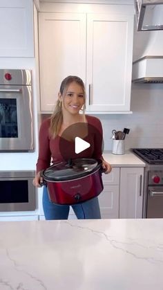 a woman holding an electric pressure cooker in her kitchen