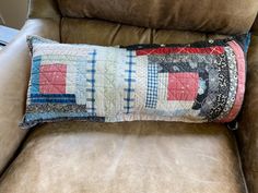 a patchwork pillow sitting on top of a brown chair