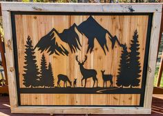 a wooden sign with deer and mountains on it