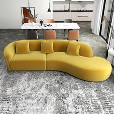 a yellow couch sitting in the middle of a living room next to a dining table