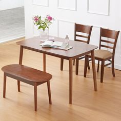 a wooden table with two chairs and a vase filled with flowers on top of it