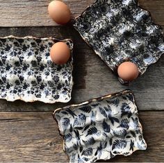 three black and white dishes with eggs in them on a wooden surface, next to one another