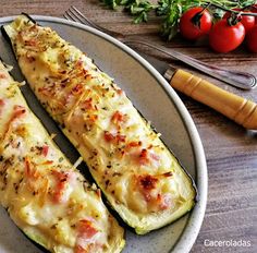 two zucchini boats on a plate with tomatoes and parsley in the background