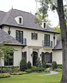 a large white house with brown shutters on the front and side windows is shown