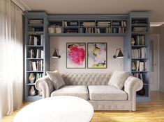 a white couch sitting in front of a book shelf filled with lots of books next to a window