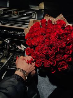 a woman is holding a bouquet of red roses in her hand while sitting next to an oven