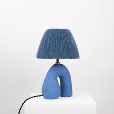 a blue lamp sitting on top of a white table next to a black corded light