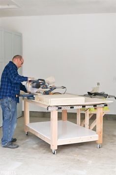 a man working on a workbench in a room that is being remodeled with white paint