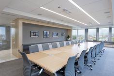 an empty conference room with large wooden table and grey chairs, looking out the window