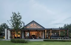 a house that is sitting on top of a lush green field with trees in the background