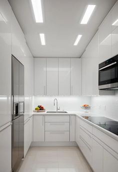 an empty kitchen with white cabinets and stainless steel appliances in the center, is shown