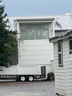 a white house sitting on the side of a road next to a truck parked in front of it