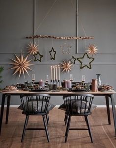 a dining room table with two chairs and a star decoration hanging from it's ceiling