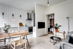 a kitchen and living room are shown with white tile on the walls, wood floors, and flooring