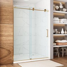 a bathroom with a glass shower door and white rugs on the wooden flooring