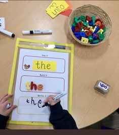 a person is writing on a piece of paper with magnets and crayons