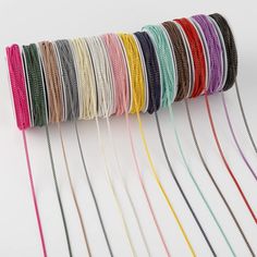 a roll of multicolored thread on a white surface with several colors in the background