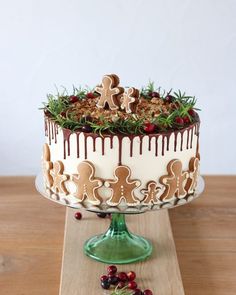 a decorated cake sitting on top of a wooden table next to cranberries and nuts