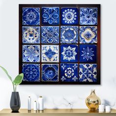 a blue and white tile wall hanging above a wooden table with vases on it