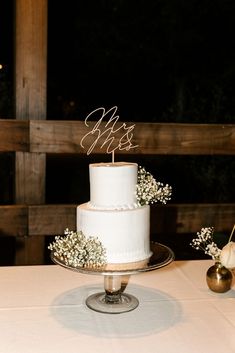 a white wedding cake sitting on top of a table next to a vase with baby's breath flowers