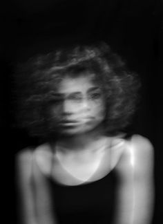 a black and white photo of a woman's face with her hair blowing in the wind