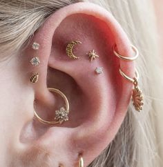 a woman wearing gold ear piercings with stars and moon designs on her left ear