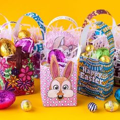 colorful easter baskets filled with chocolate eggs and candies on a yellow background, decorated with bunny ears