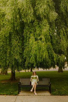 a woman sitting on a bench under a tree