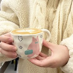 a person holding a cup with some sort of animal design on it's side