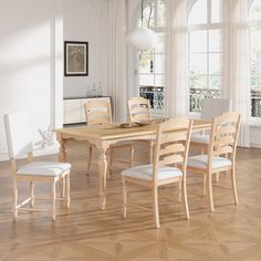 a dining room table and chairs in front of large windows