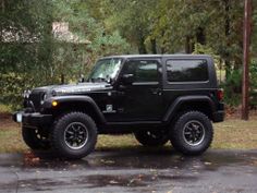 a black jeep is parked in front of some trees