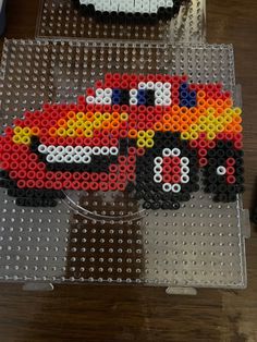 two lego cars are sitting on top of a plastic tray, each with different colored beads