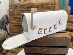 a white mailbox sitting on top of a pile of wooden pallets with letters that spell out the word cats