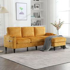 a living room scene with focus on the yellow couch and rug, which is in front of a large window