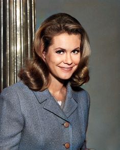 a woman wearing a blue coat and smiling at the camera