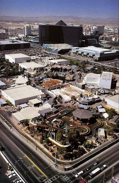 an aerial view of a city with lots of buildings and cars on the road in front of it