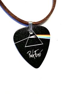 a guitar pick with the pink floyd logo on it is hanging from a brown cord