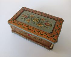 an ornately decorated wooden box sitting on top of a white table with no one around it