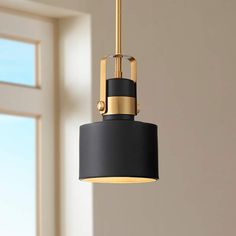 a black and gold pendant light hanging from a ceiling in a room with large windows